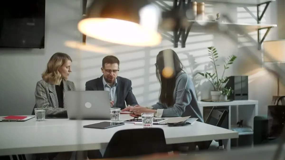 A team meeting around a table with laptops
