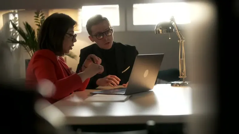 A woman and a man going through a case together at a laptop