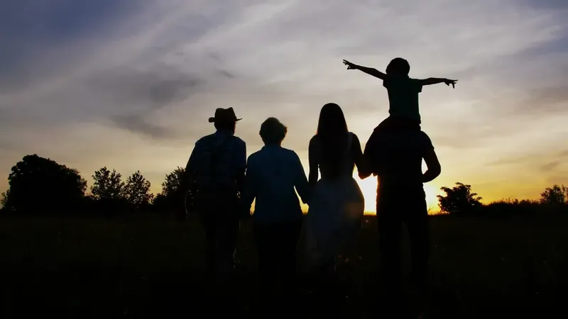 A family walking together at sunset, a child on his father's shoulders