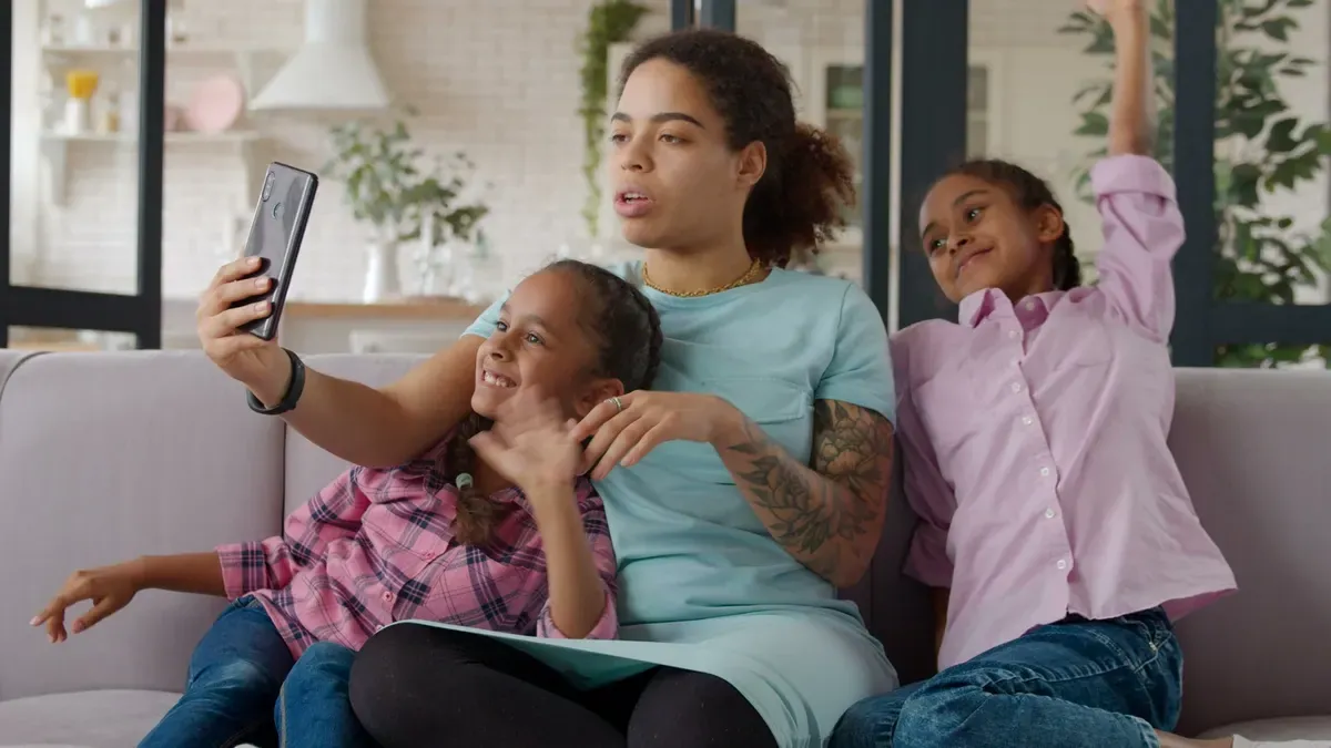 A mother taking a selfie with her two daughters on the sofa