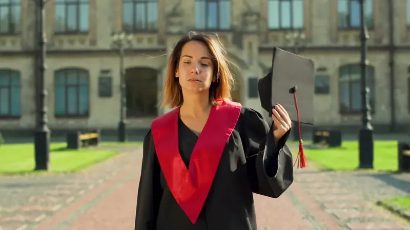 A graduate in cap and gown outside a university