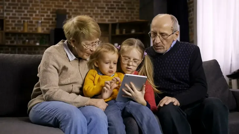 Grandparents sharing a tablet with their two granddaughters
